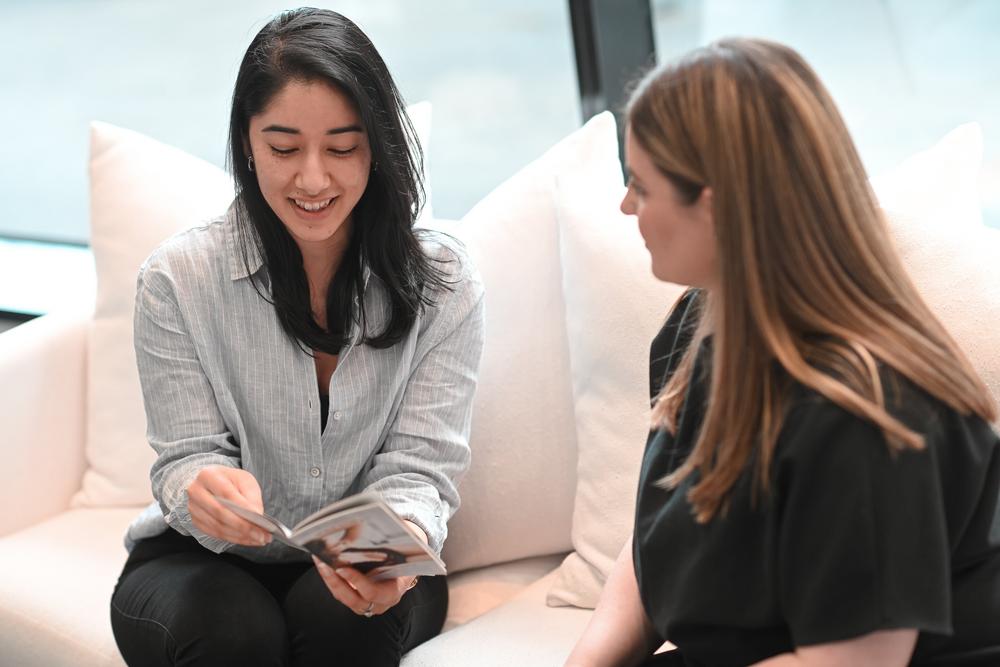 A skin clinic client is sitting on a white couch.  Skin therapist and facialist Natasha is speaking to her about her skin concerns.  This is part of a skin consultation at Natashas Skin Spa on City Road in Southbank Melbourne Australia.